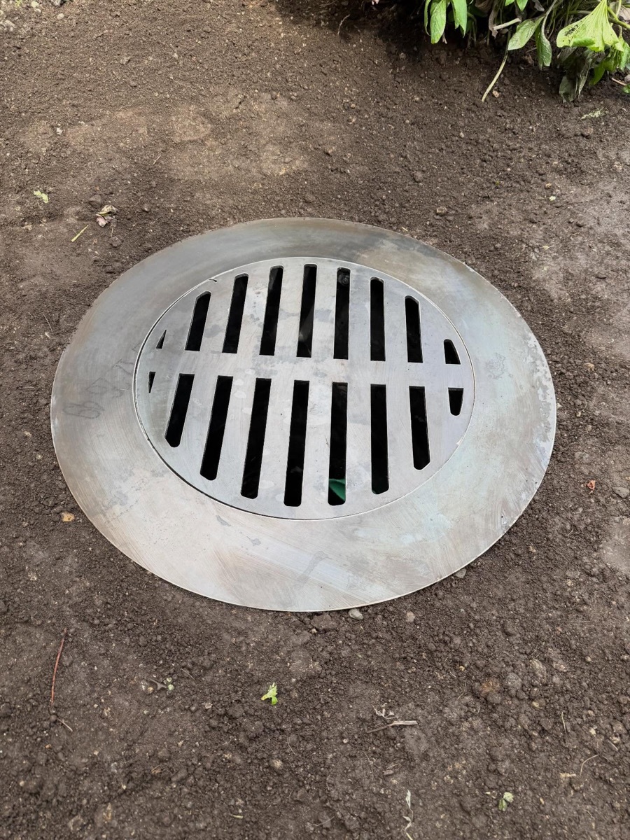 Round custom catch basin cover set into the ground