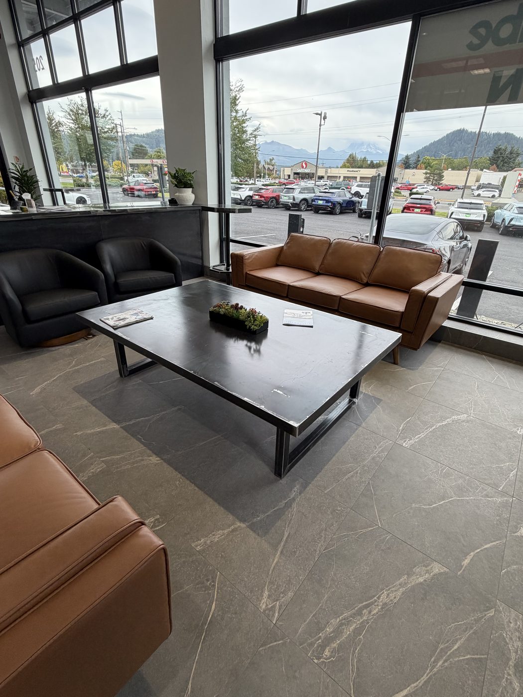 Black steel coffee table in a showroom lounge between leather sofas